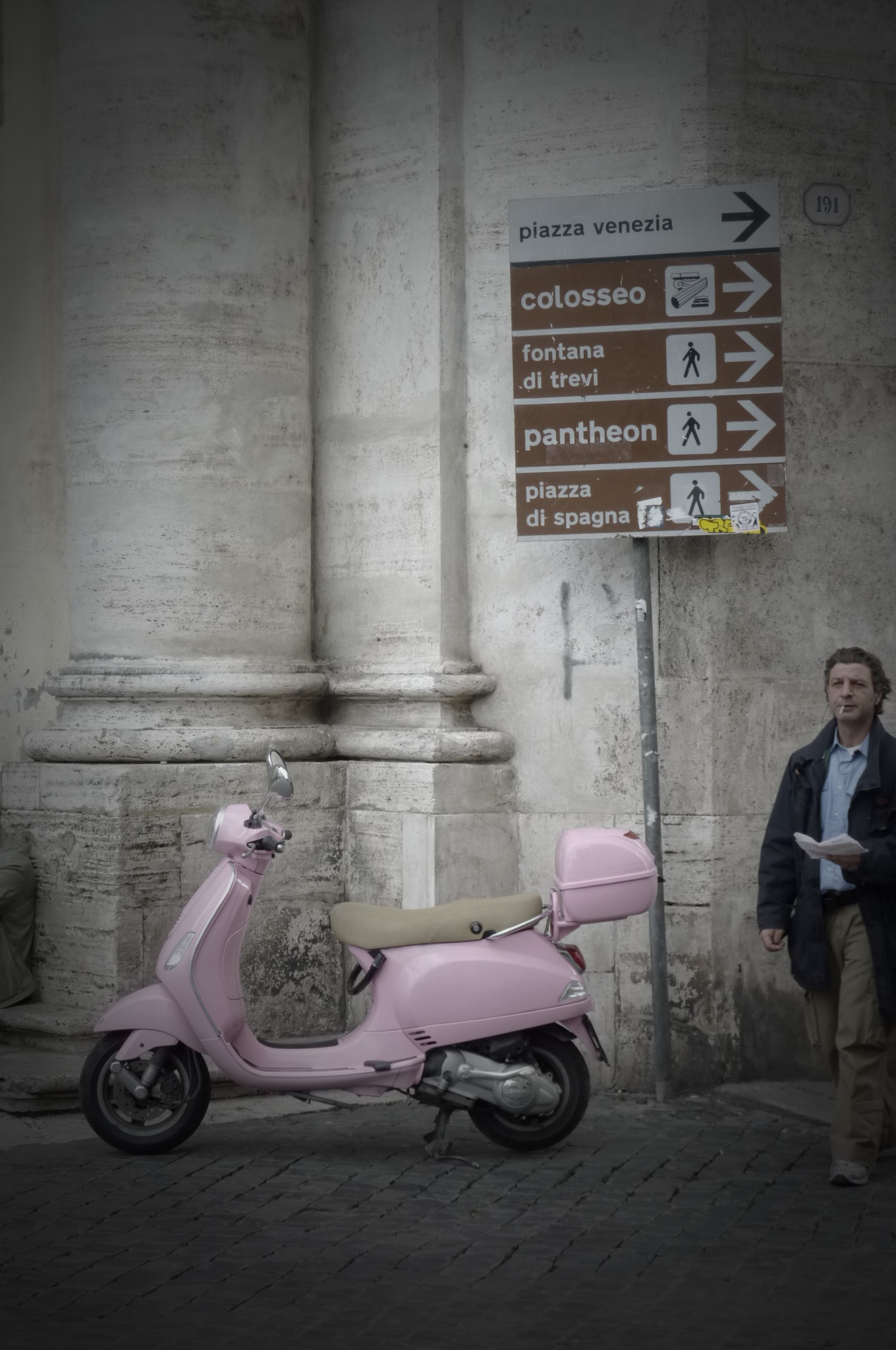 A Roman walks past a pink motorino in Rome