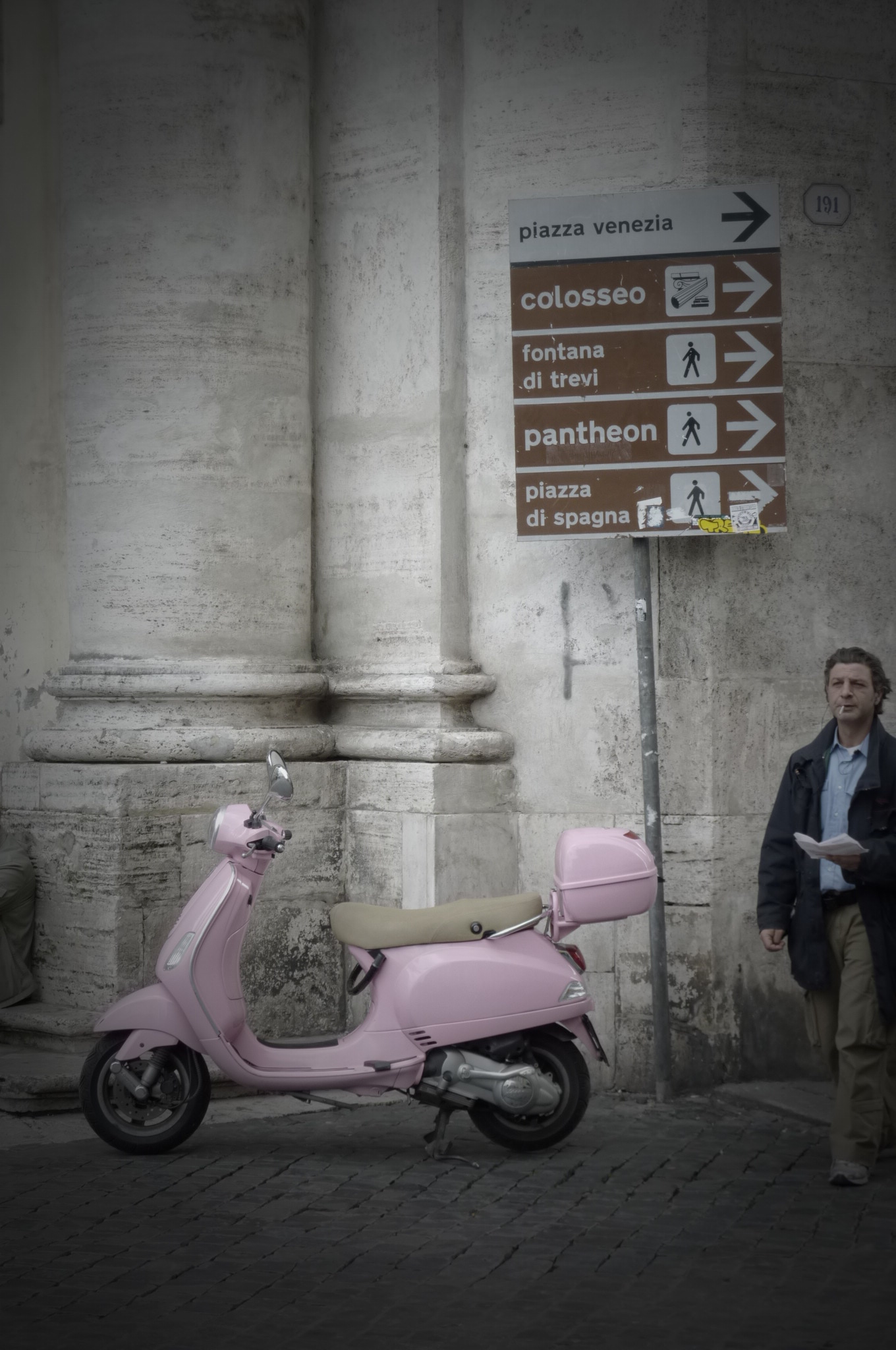 A Roman walks past a pink motorino in Rome